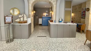 A modern kitchen with a central island, a stone archway, and a tiled floor. - Amiral (Paris)