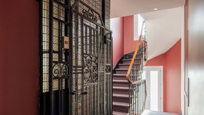 Una escalera con barandal metálico y una reja decorada en la parte superior.