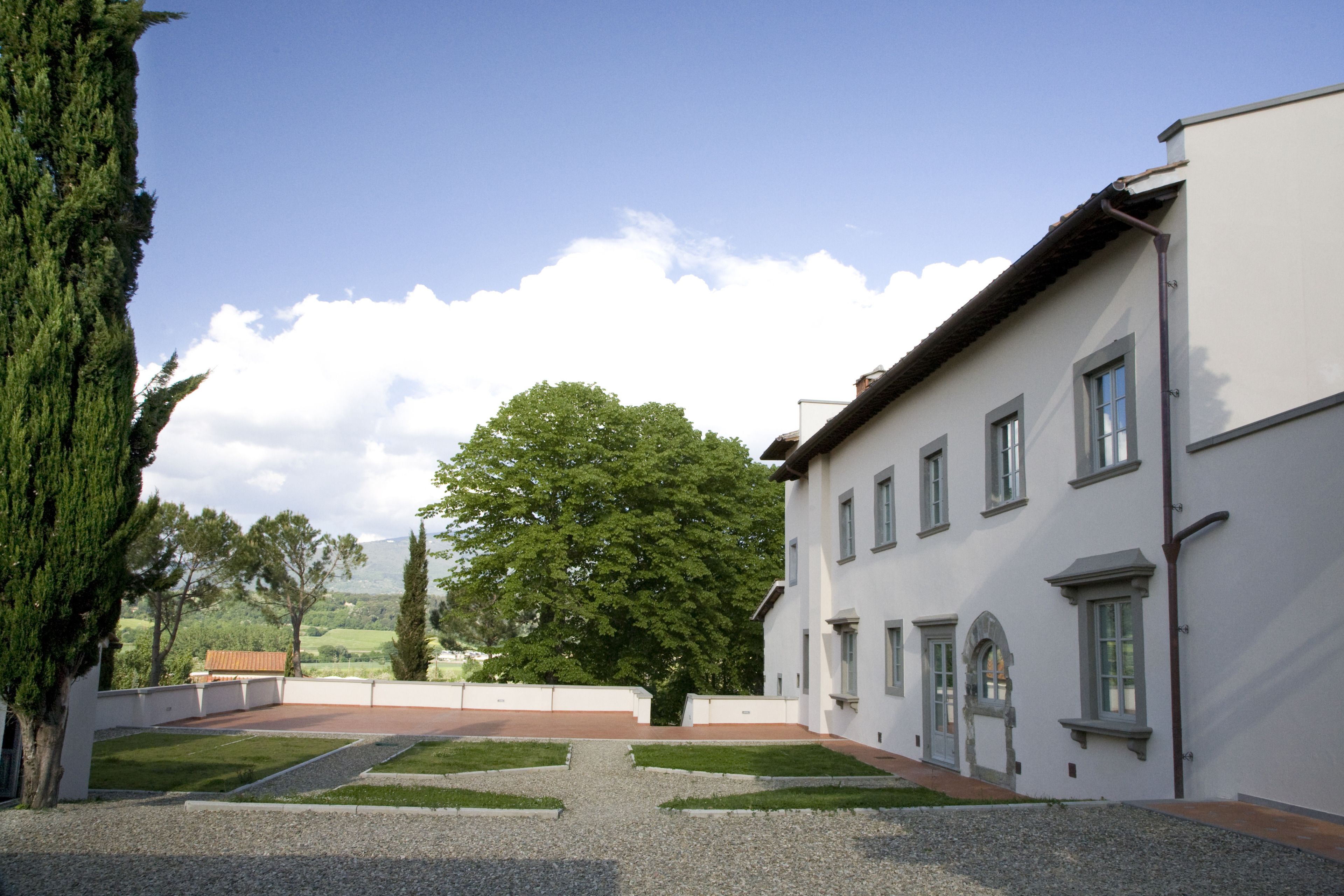 A courtyard with a gravel path leading to a building with multiple windows and a door.