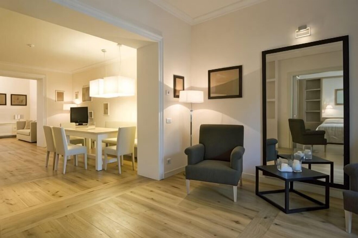 Un salon moderne comprenant un coin repas, un grand miroir et un téléviseur à écran plat.
