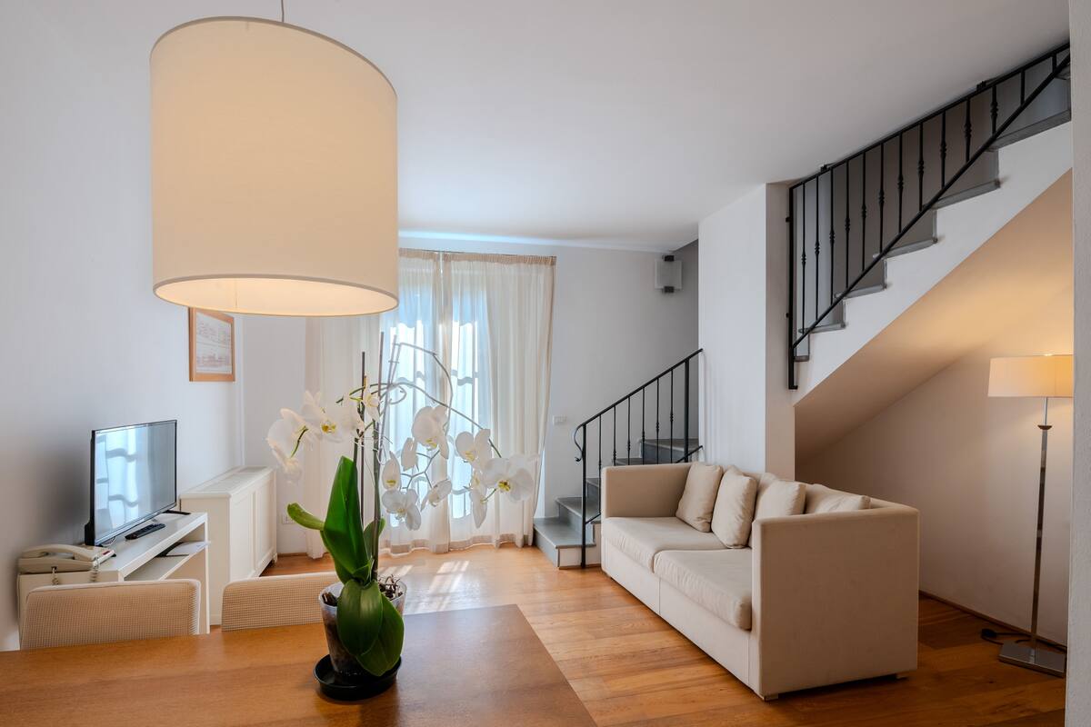Una sala moderna con un sofá, una mesa de centro, un televisor y una escalera.