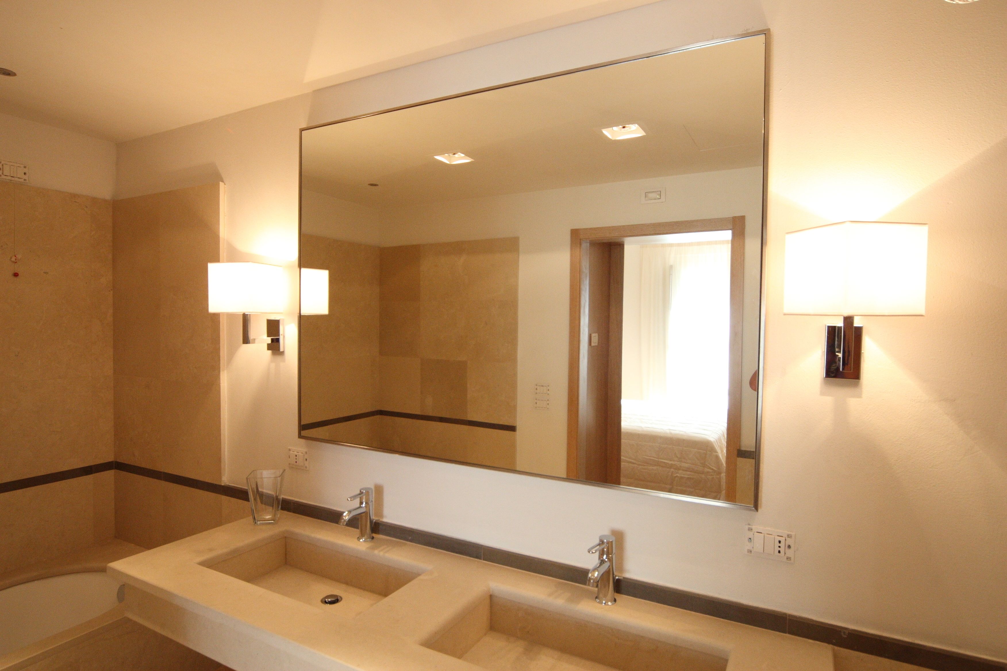 A hotel bathroom with two sinks, a large mirror, and wall-mounted lights.