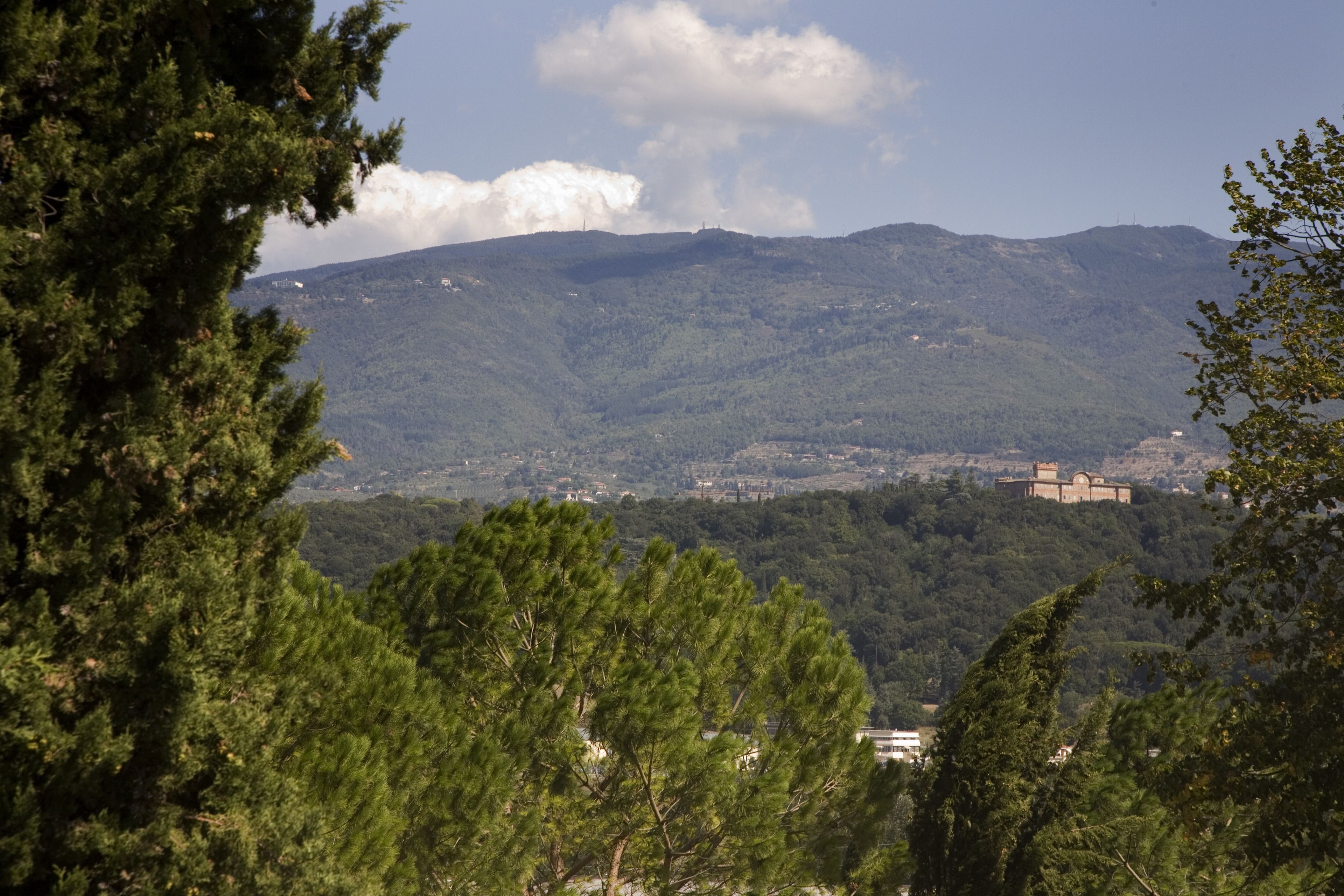 A mountainous landscape with a historic building on a hill.