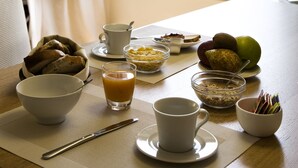 Uma mesa de café da manhã com tigelas de cereal, um copo de suco de laranja e uma xícara.