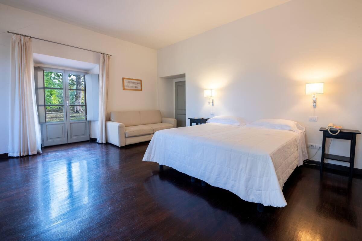 Una habitación de hotel con cama, sofá, escritorio y lámpara.