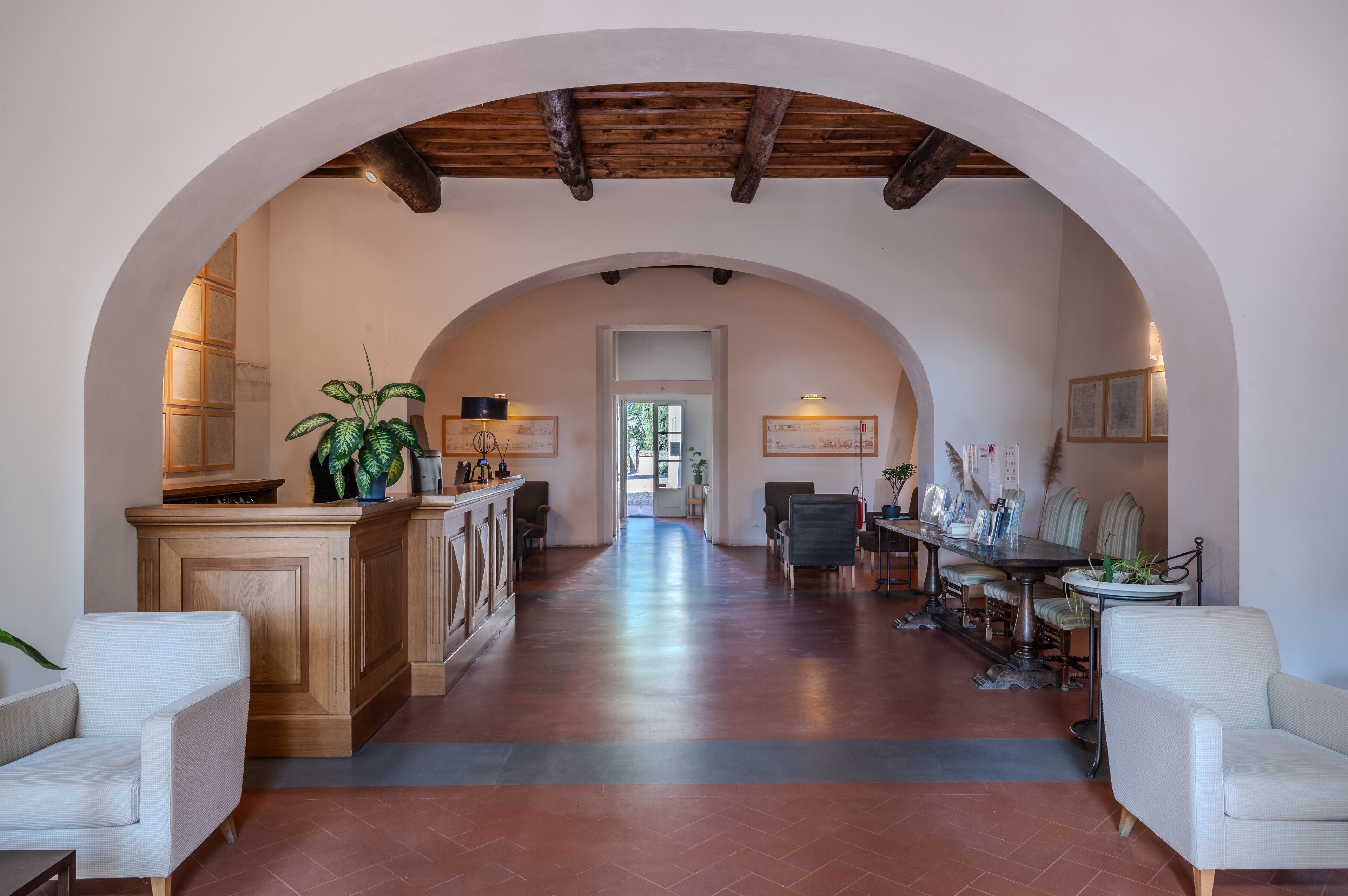 A spacious hallway with an arched ceiling, wooden cabinets, and seating areas.
