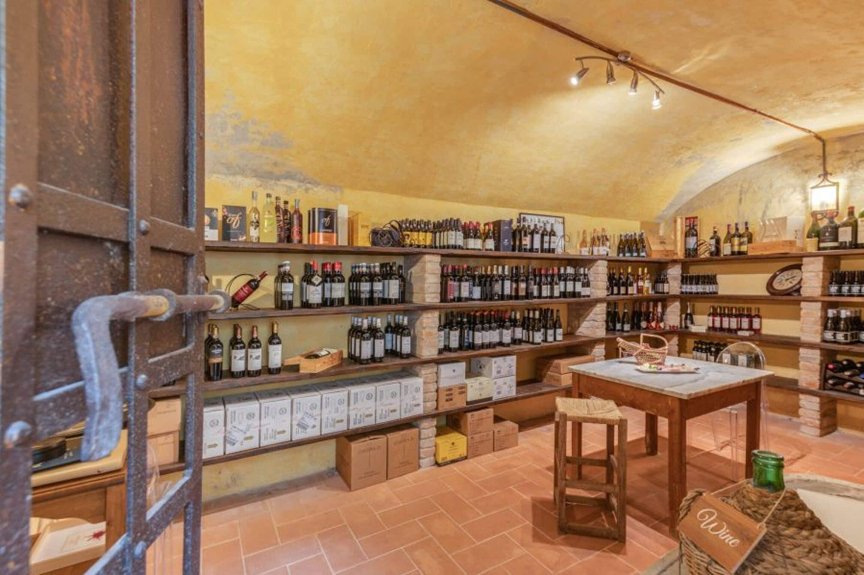 A wine cellar with shelves stocked with wine bottles, a wooden table, and a ladder.