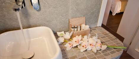 A bathroom with a white sink, two faucets, and a wooden box with toiletries.