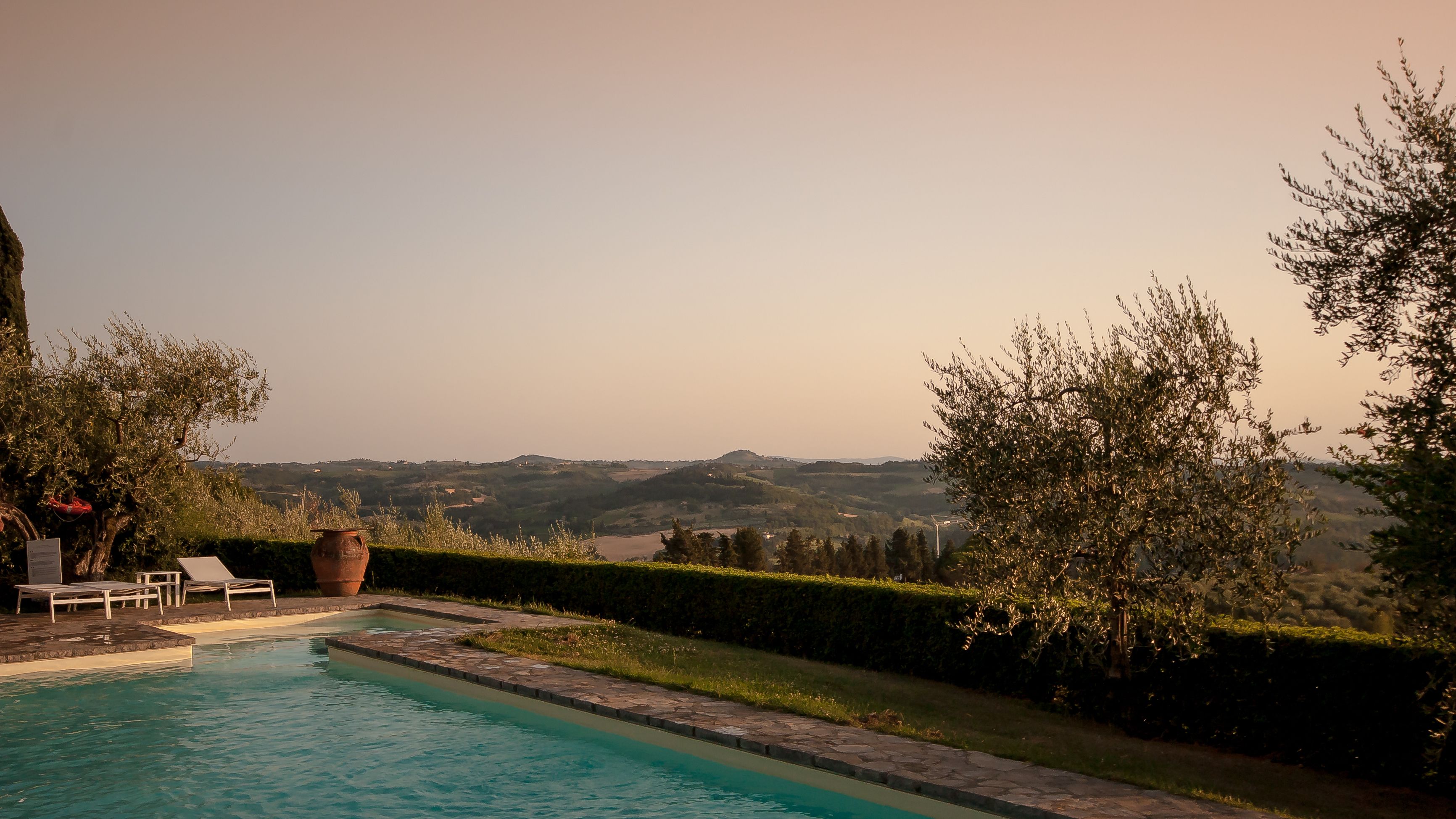 A swimming pool with lounge chairs and a view of the countryside.