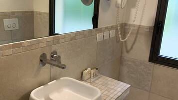 A bathroom with a white sink, a glass shower enclosure, and a tiled floor.