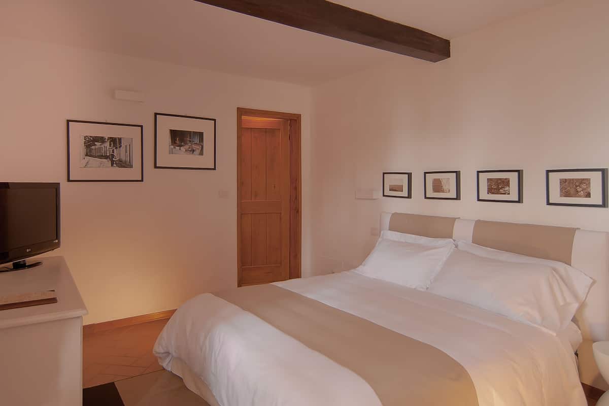 Un dormitorio con una cama, un televisor y cuadros en la pared.