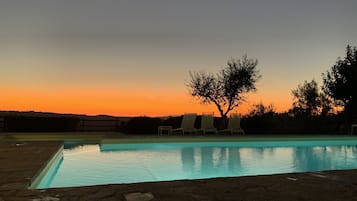 Una piscina al aire libre, sombrillas, sillones reclinables de piscina