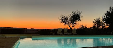 Una piscina al aire libre, sombrillas, sillones reclinables de piscina