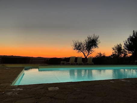 Una piscina al aire libre, sombrillas, sillones reclinables de piscina