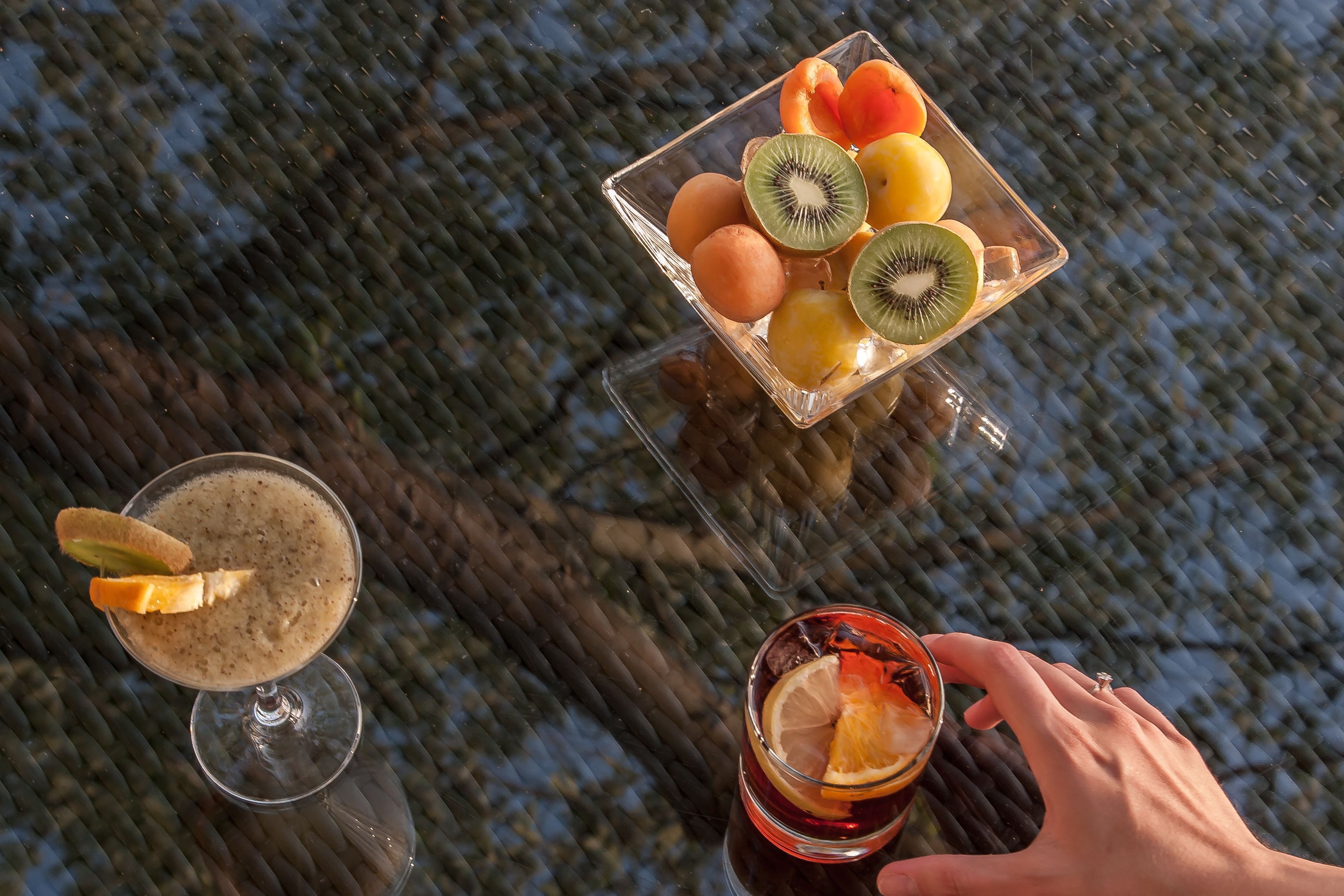 A table with a fruit bowl and two drinks.