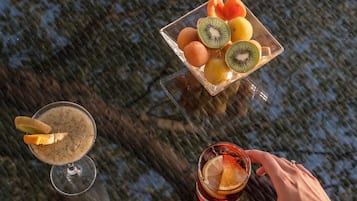 A table with a fruit bowl and two drinks.