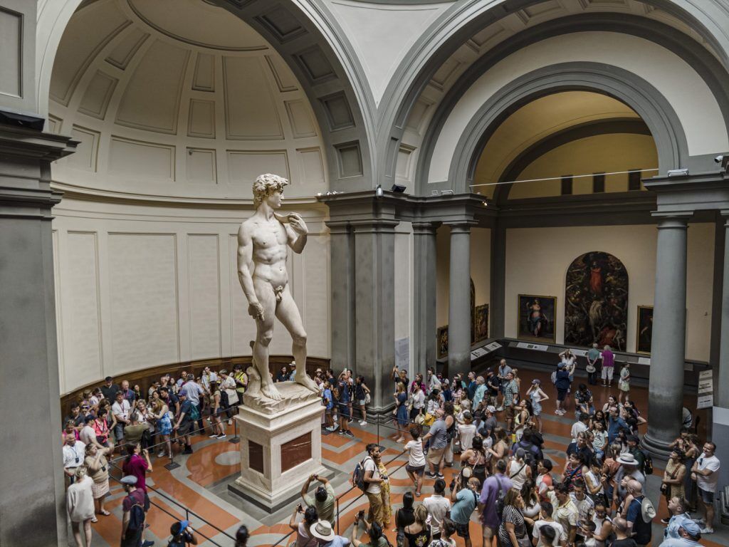 Une grande statue de marbre se dresse dans un vaste atrium aux hauts plafonds et à l’architecture classique.