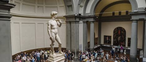 A large marble statue in a spacious atrium with high ceilings and classical architecture.