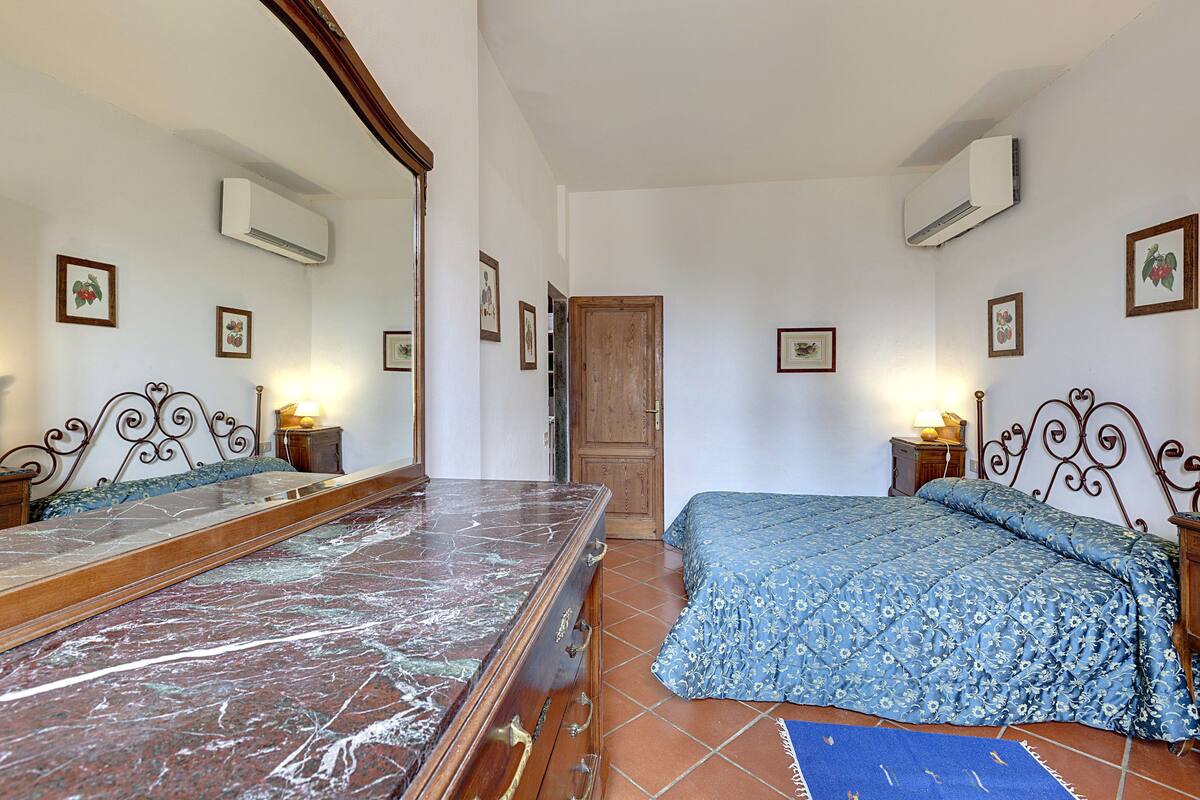 Un dormitorio con una cama grande, un aparador de madera, un espejo y una puerta.