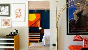 Una habitación de hotel moderna con una cama, mesita de noche y un cartel grande en la pared.