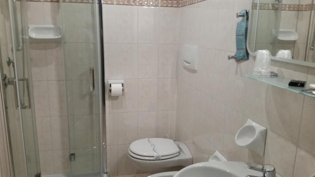 Un baño con cabina de ducha de vidrio, inodoro, lavabo y espejo.