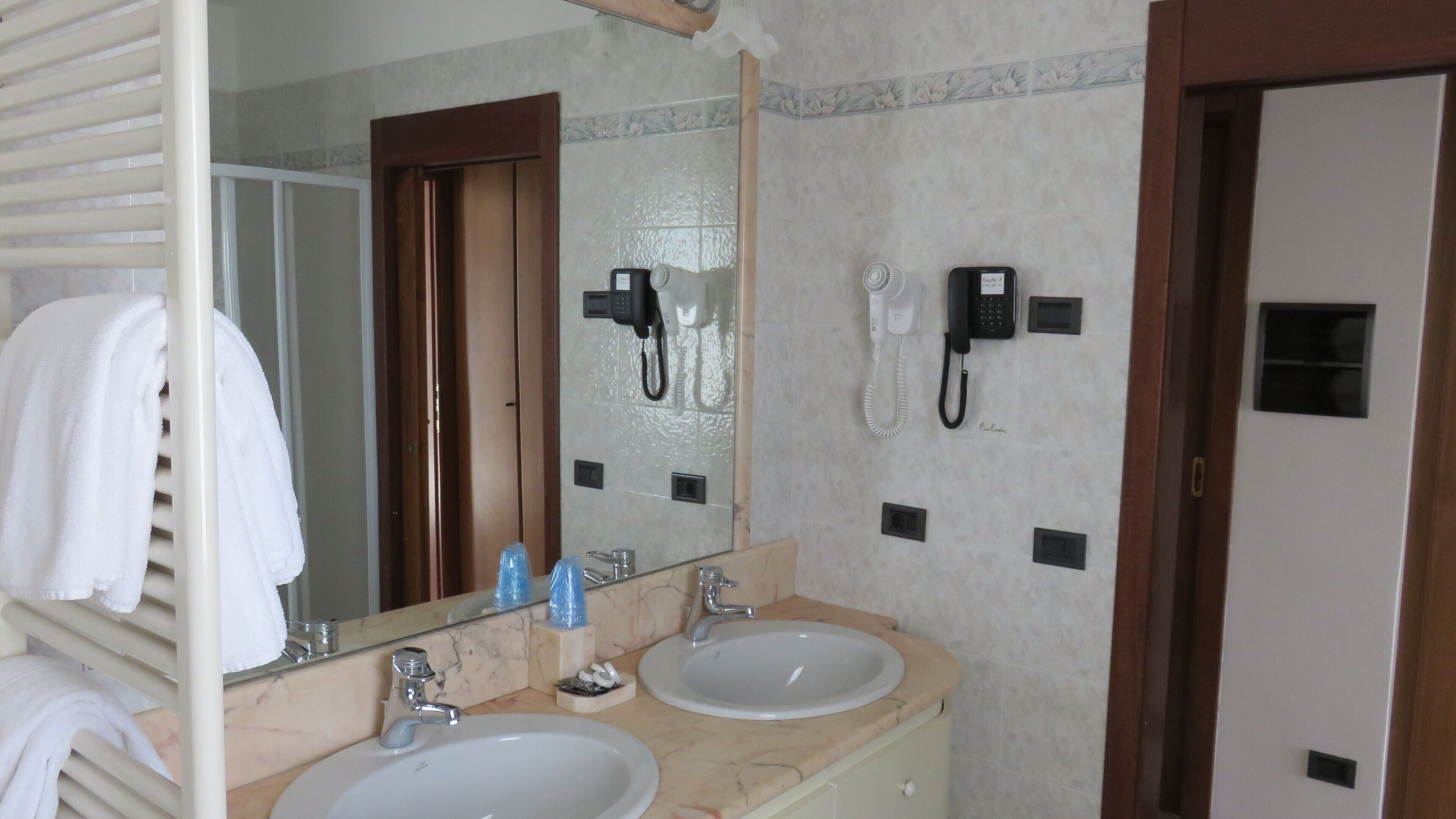 Ein Badezimmer mit zwei Waschbecken, einem Spiegel und zwei an der Wand befestigten Telefonen.
