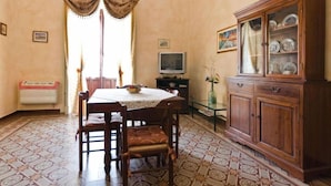 A dining area with a table, chairs, a cabinet, and a television. - Etna Bed & Breakfast (Belpasso)