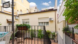 A courtyard with a table and chairs, surrounded by buildings with balconies and potted plants. - Etna Bed & Breakfast (Belpasso)