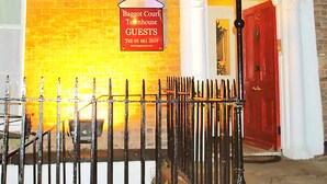 A brick building with a sign for Baggot Court Townhouse Guests, a red door, and a black iron fence in front. - Baggot Court Townhouse (Dublin)