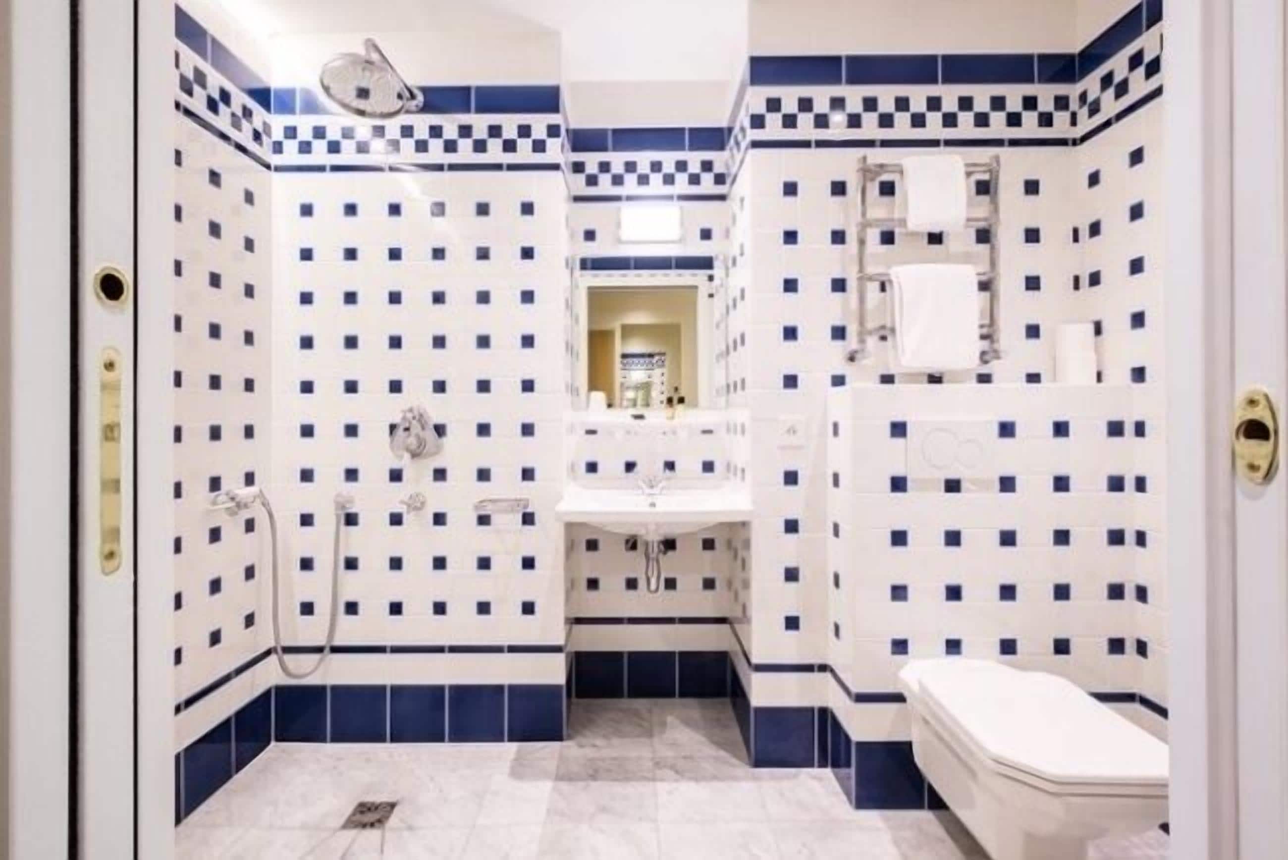 Un baño con piso de baldosas a cuadros, un lavamanos, un inodoro y una ducha.