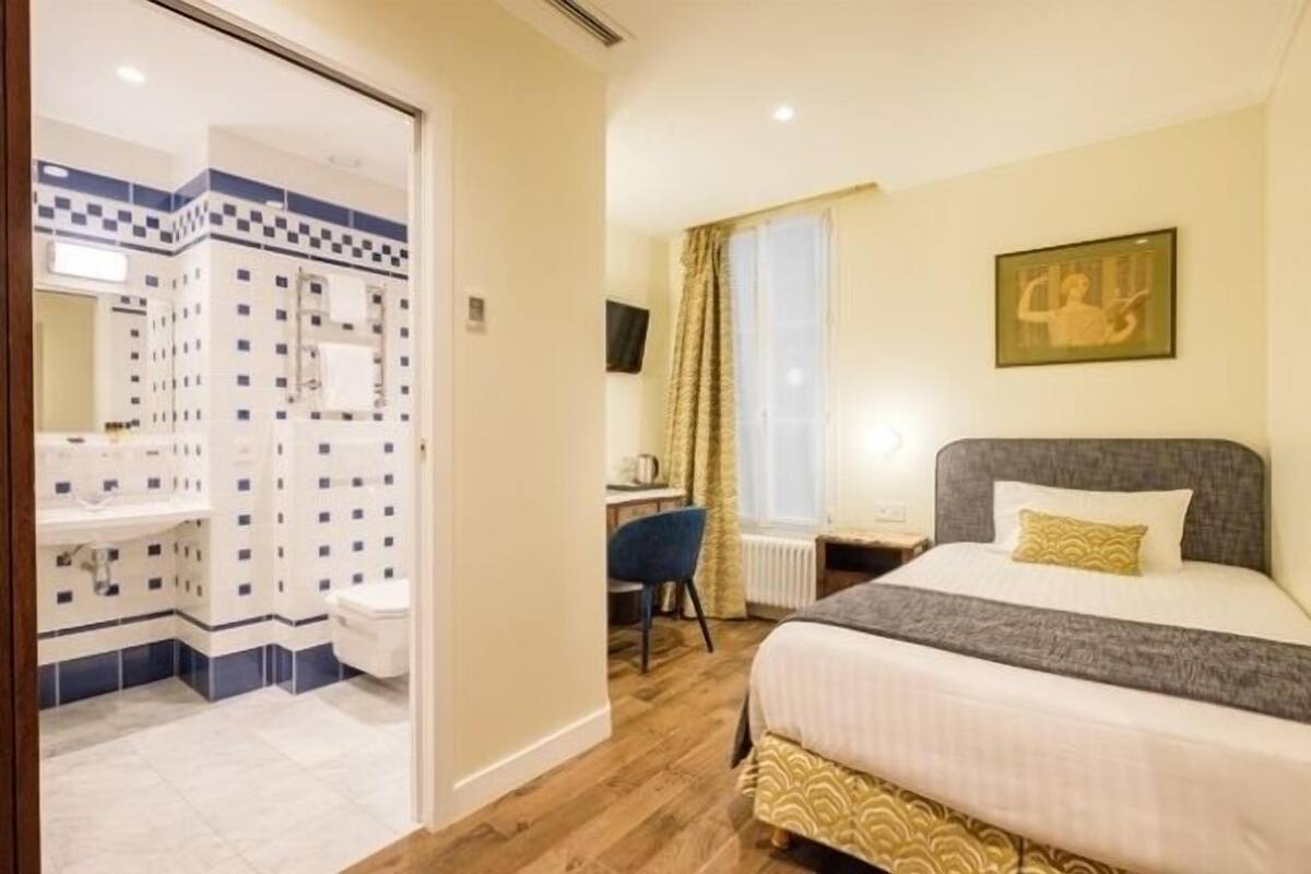 A hotel room with a bed, a desk, a chair, and a bathroom.