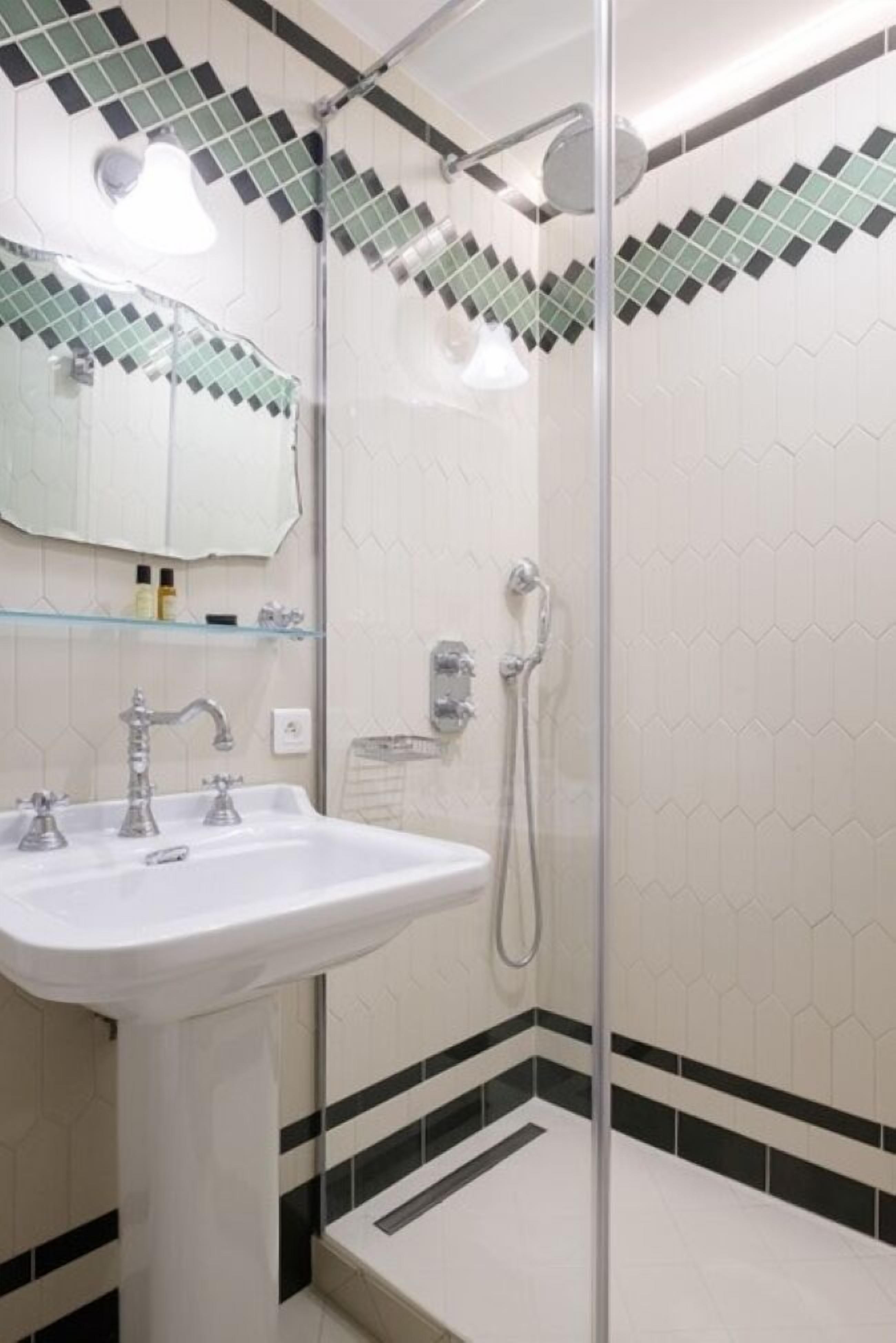 A bathroom with a glass-enclosed shower, a white sink, and a mirror above it.