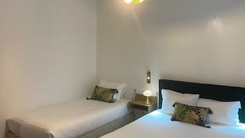 A hotel room with two single beds, a small table, and a lamp.