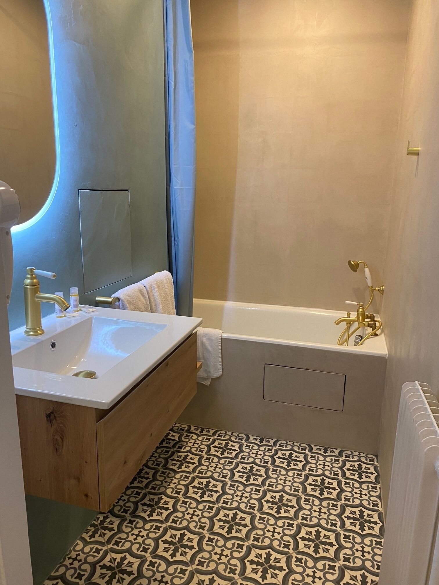 Ein Badezimmer mit Waschbecken, Waschtisch, Badewanne und Fliesenboden mit Muster.