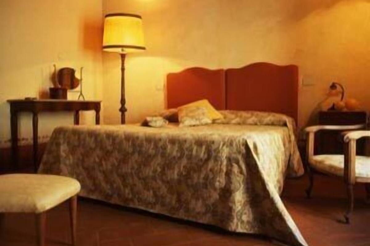 Un dormitori amb un llit, una tauleta de nit, una làmpada i una cadira.