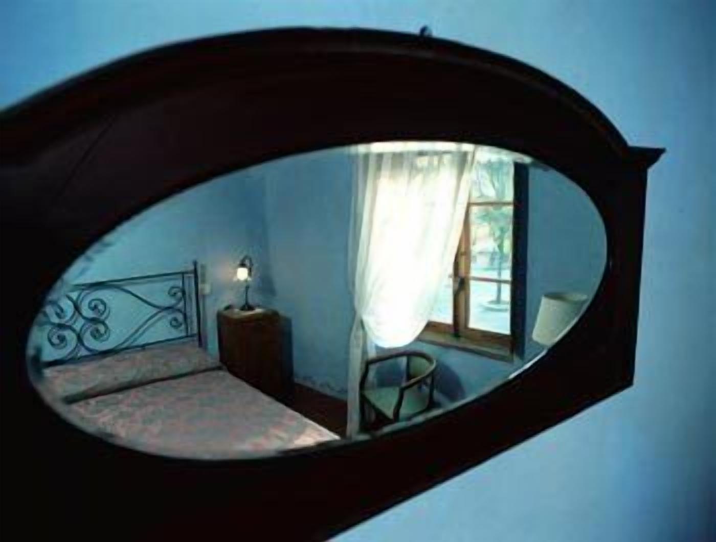 A room with a bed, a nightstand, a lamp, and a window with curtains.