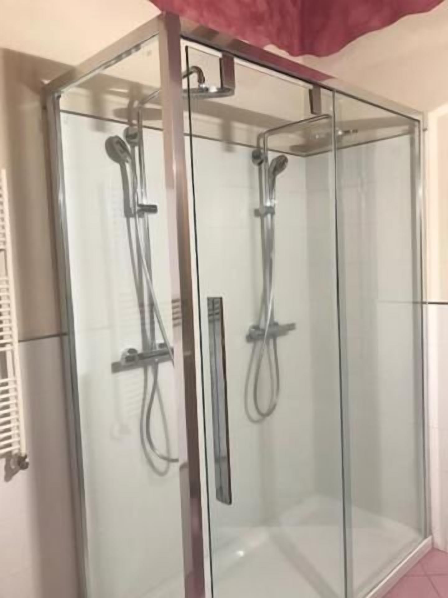 Box doccia in vetro con soffione a mano e soffione fisso.