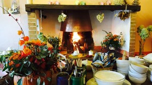 Una habitación acogedora con chimenea, una mesa servida con vajilla y varios objetos decorativos.