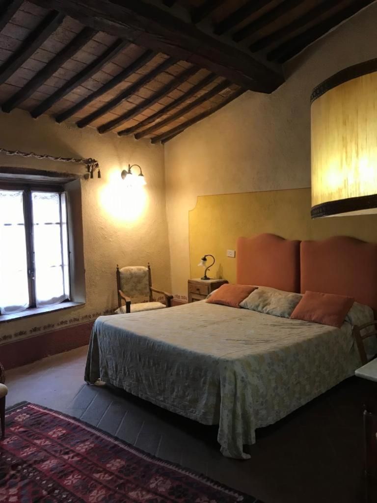 Un dormitorio con una cama, una silla, una mesita de noche, una lámpara, un ventanal y techo de madera.