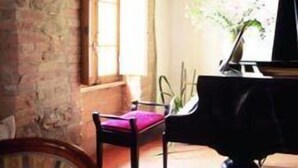 Una habitación con un piano, una ventana y una pared de ladrillo.