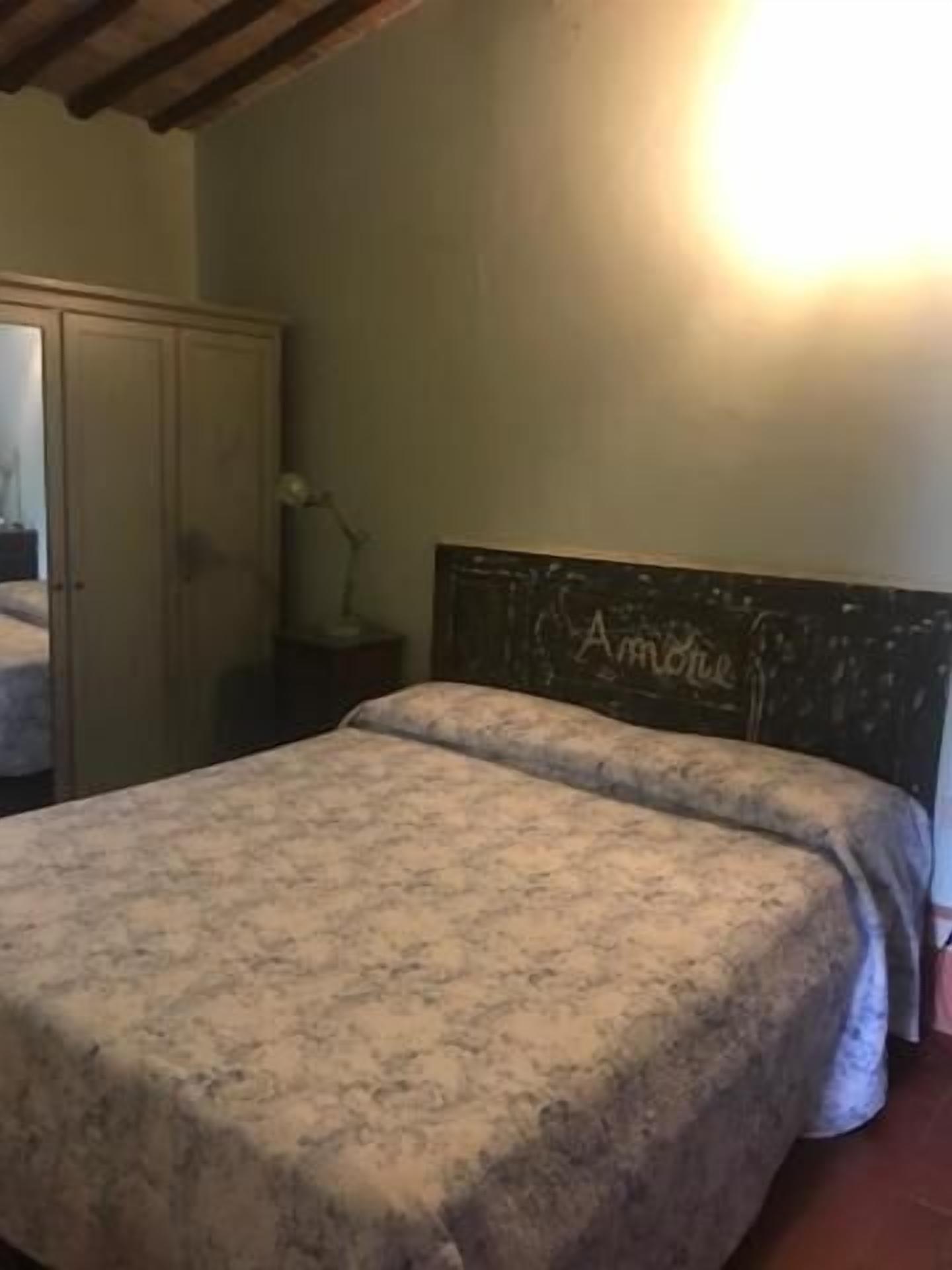 A bedroom with a bed, a wardrobe, and a nightstand.