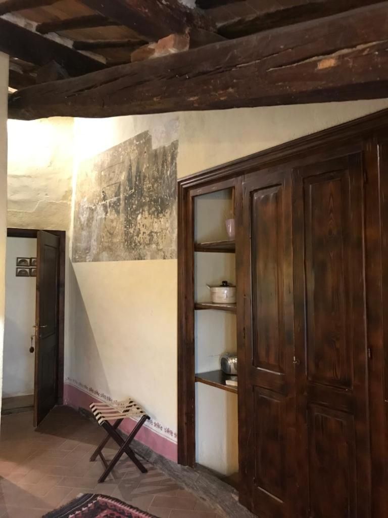 A rustic room with a wooden ceiling, a stone wall, and a wooden cabinet with shelves.