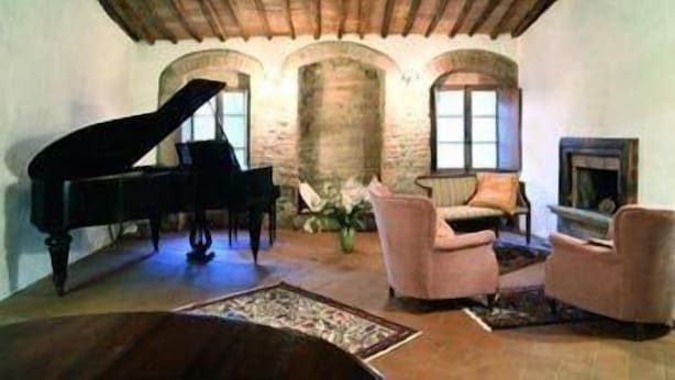 Una habitación con un piano de cola, una chimenea y una pared de piedra.
