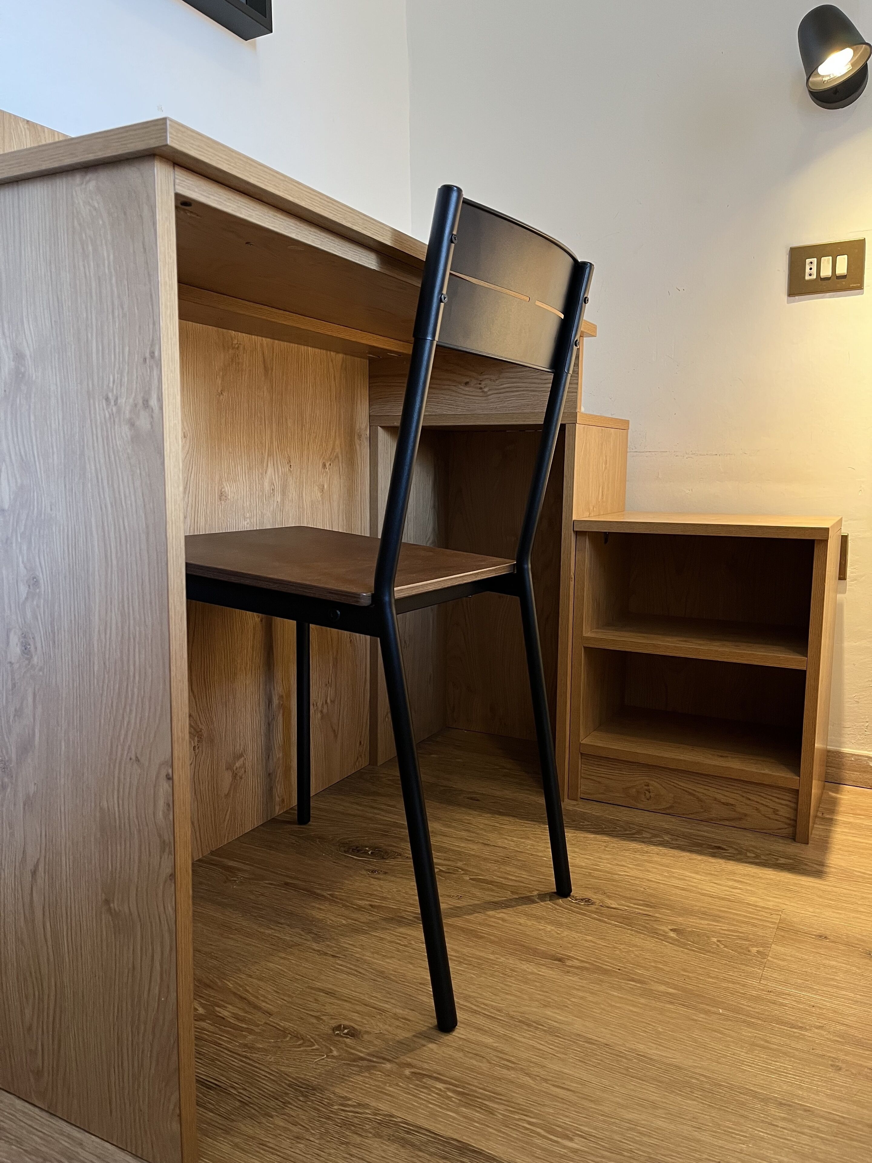 Un angolo di stanza con una scrivania in legno e una sedia.