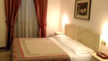 Ein Hotelzimmer mit einem Bett, einem Nachttisch, einem Telefon und einem Bild an der Wand.