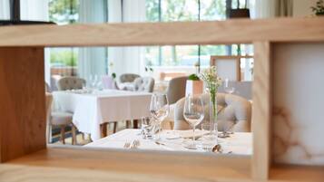Un espace repas avec des tables dressées pour deux personnes, agrémenté de nappes blanches, de verres à vin et de couverts.