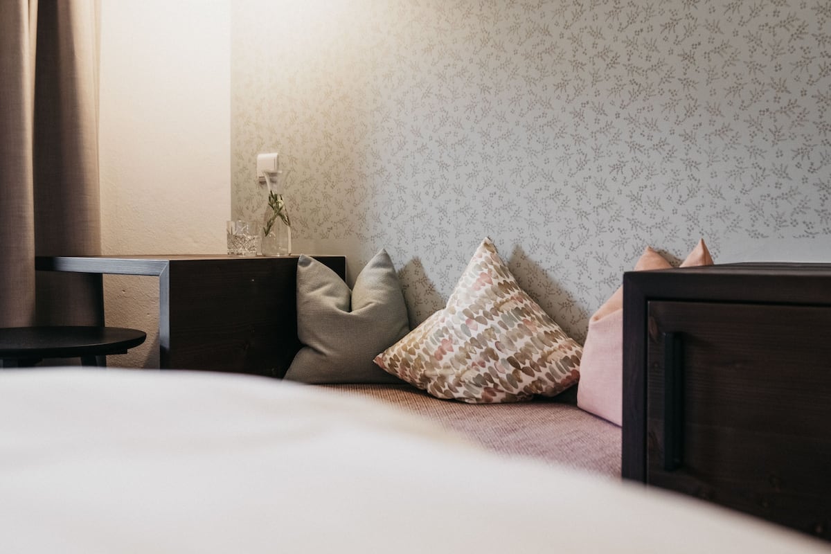 Ein ordentlich eingerichtetes Hotelzimmer mit Bett, einem kleinen Tisch und einem Nachttisch.