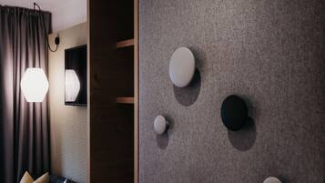 Una habitación moderna con un sofá azul oscuro, un armario de madera y una pared gris con textura y objetos redondos montados en la pared.