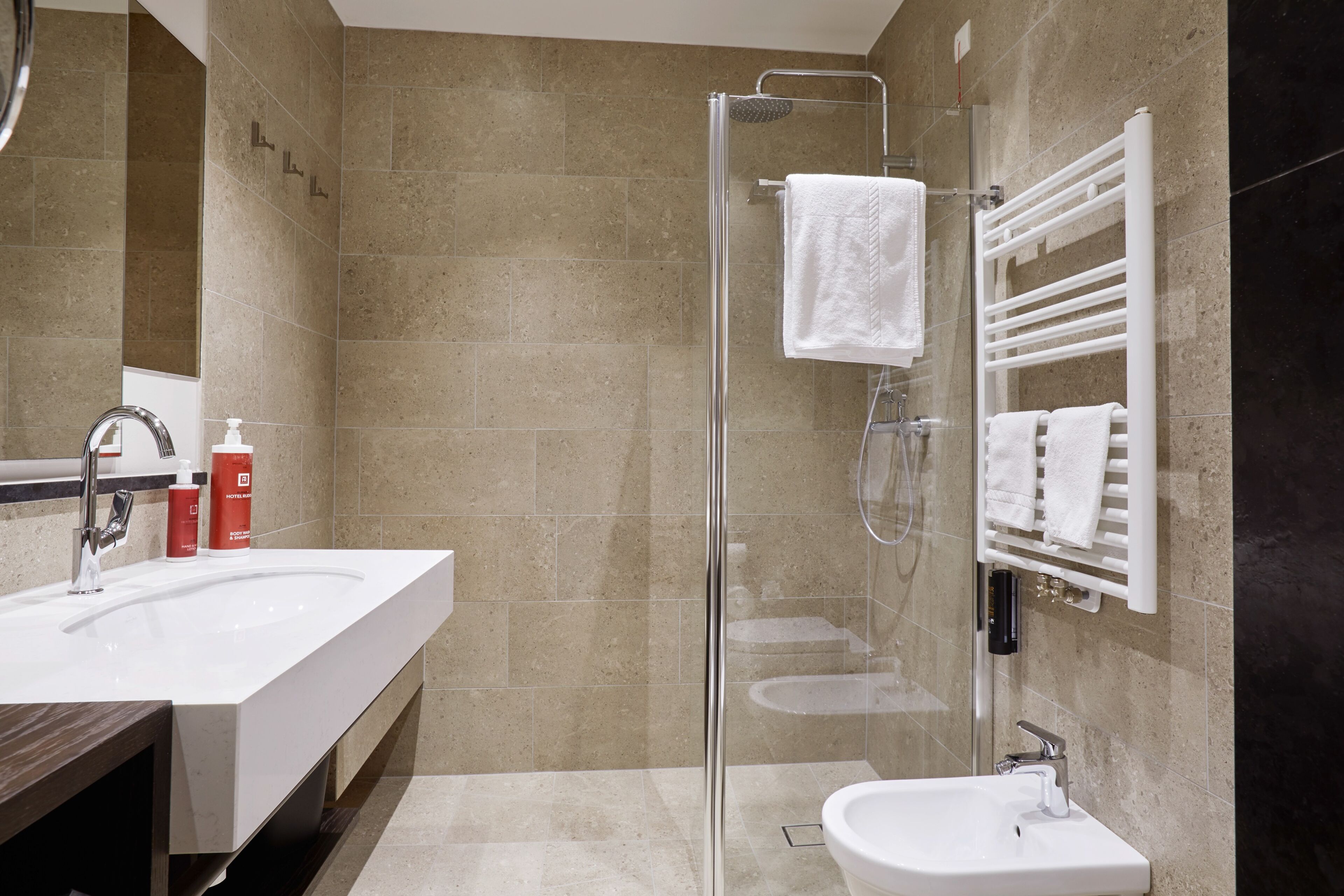 Un baño moderno con cabina de ducha de vidrio, un lavabo grande y un mueble de tocador con espejo.