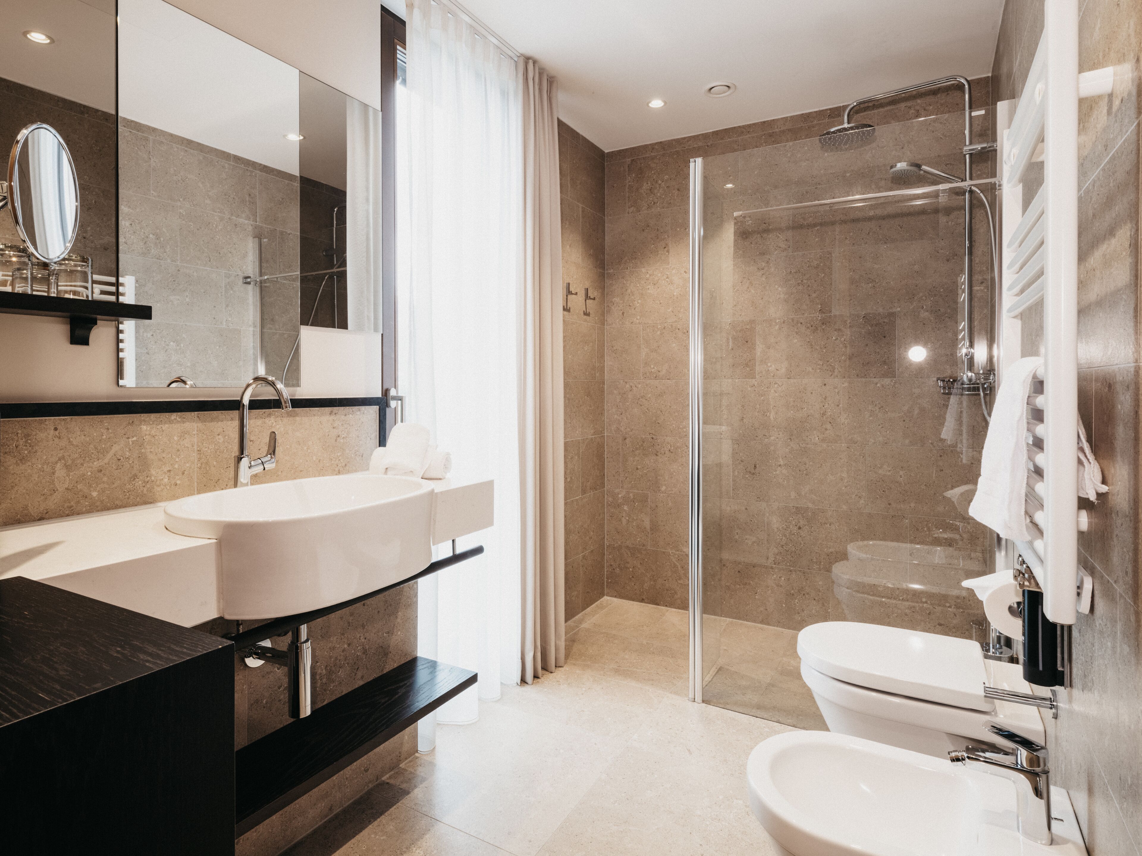 Un bagno moderno con un lavandino ampio, uno specchio e una cabina doccia.